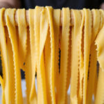 Homemade fettuccine pasta drying on a rack, made with a KitchenAid mixer.
