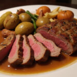 Deliciously cooked and sliced top round roast with roasted vegetables and gravy.