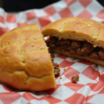 Perfect Jamaican Beef Patty cut in half showing savory filling, a delicious snack.