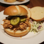 Juicy shredded Mississippi Chicken sandwich with pickles and coleslaw, a delicious and easy meal.