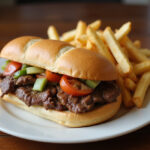 Juicy shaved beef steak sandwich with toppings and fries.