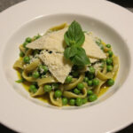 Bowl of delicious pasta and peas with Parmesan cheese and basil.