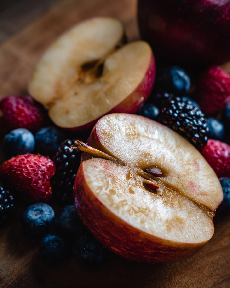 Apple slices surrounded by fresh blueberries, raspberries, and blackberries. Part of healthy snack ideas.