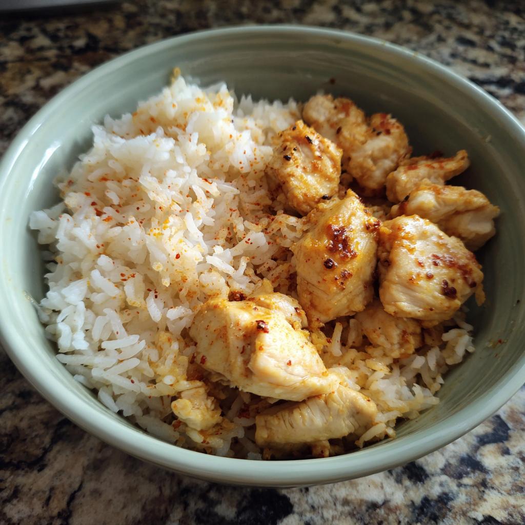 A bowl of chicken and rice recipes, featuring seasoned chicken pieces and fluffy white rice.