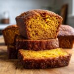 A stack of sliced cinnamon sugar pumpkin bread loaves on a wooden board.