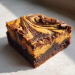 A single pumpkin cheesecake swirl brownie featuring a beautiful swirl pattern on top.