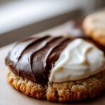 A close-up of a Snoopy black and white cookie, showing the distinct chocolate and vanilla icing.