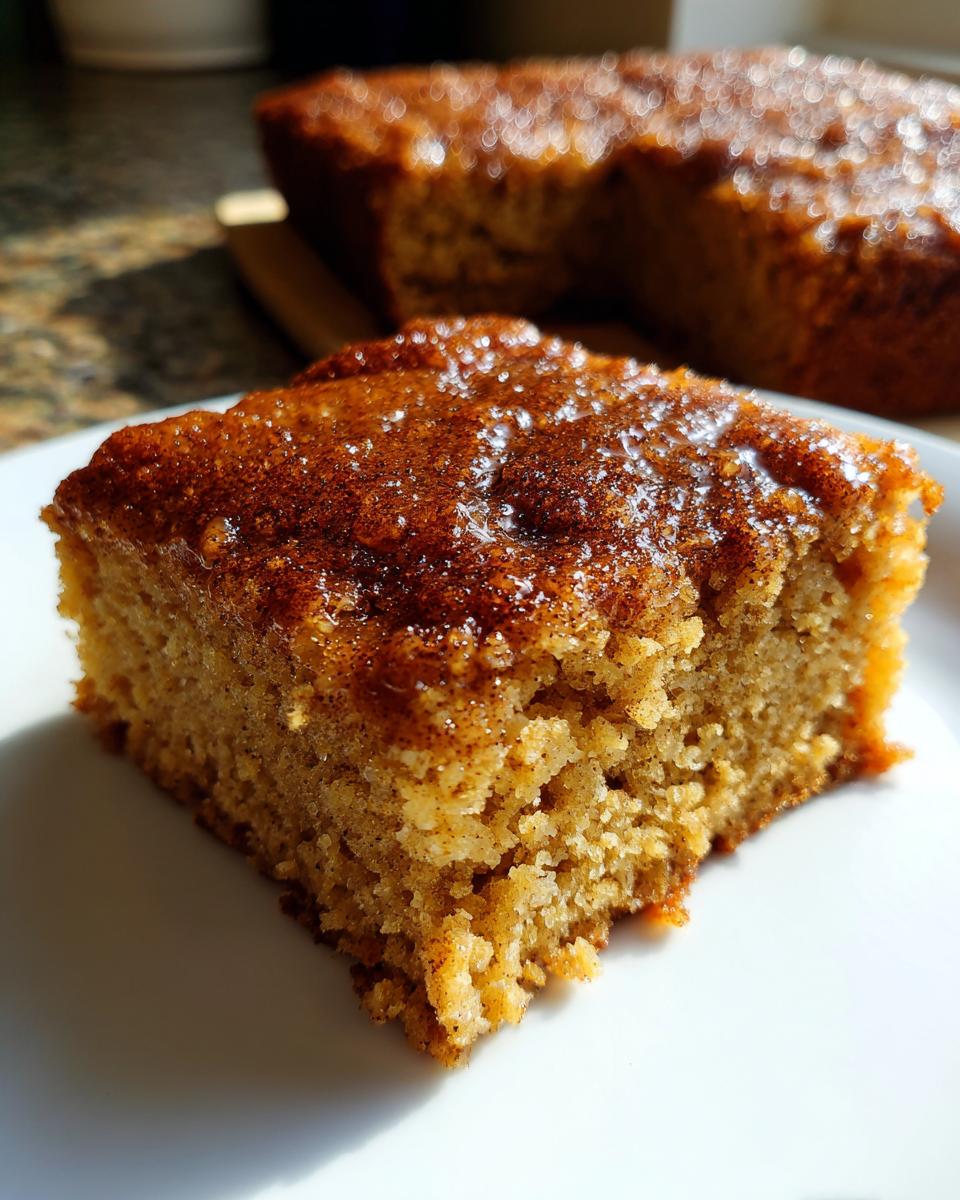 A slice of Spiced Chai Snickerdoodle Blondies on a white plate, showing its texture and cinnamon topping.