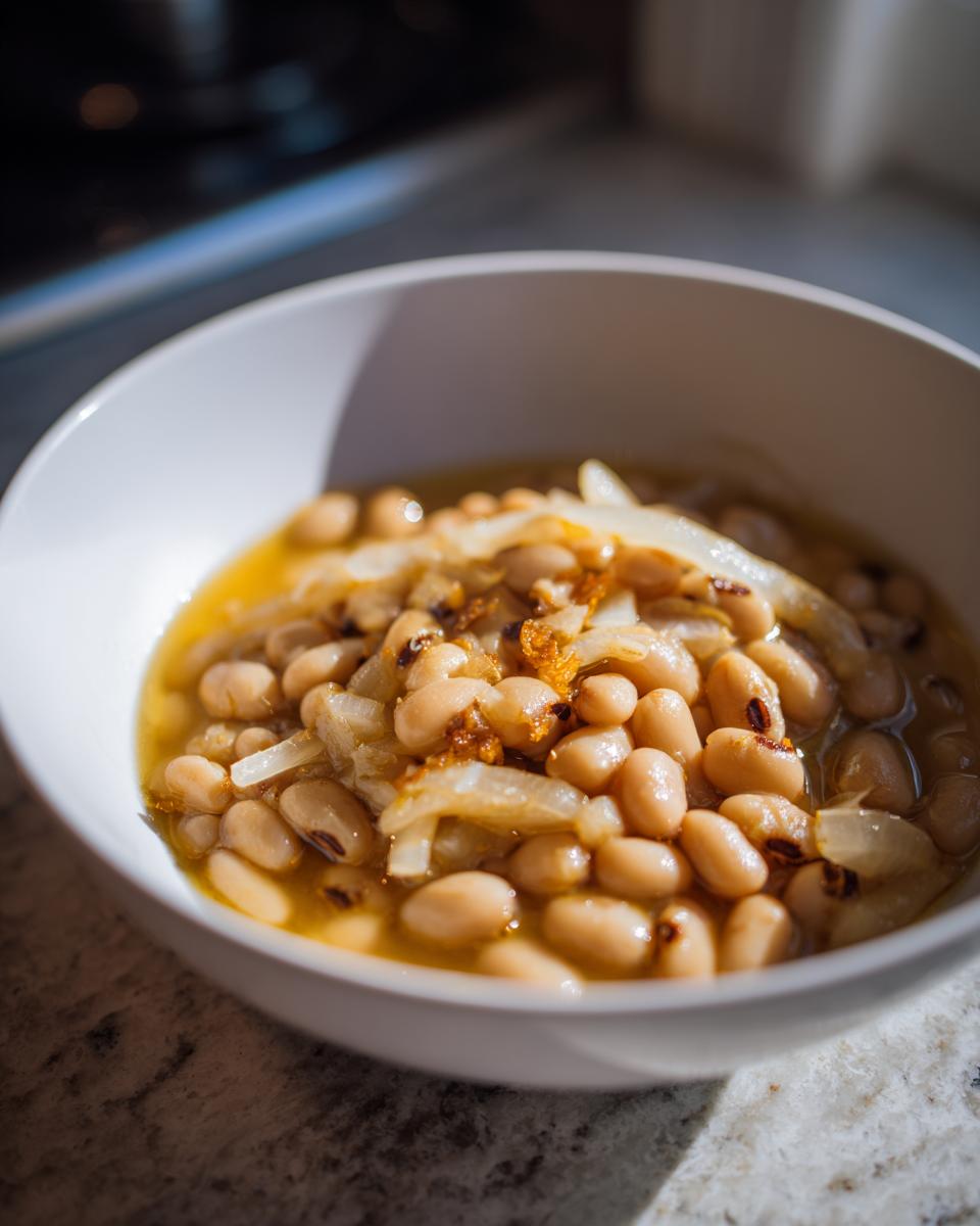 Close-up of a white bowl filled with a comforting black eyed peas recipe, featuring tender beans and sautéed onions.