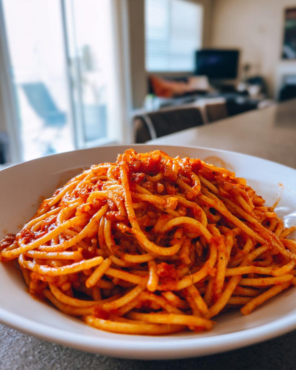 A close-up of a white bowl filled with spaghetti and a rich tomato meat sauce, perfect for easy dinner ideas.