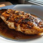 A glistening garlic butter chicken breast served in a white bowl with a rich sauce.