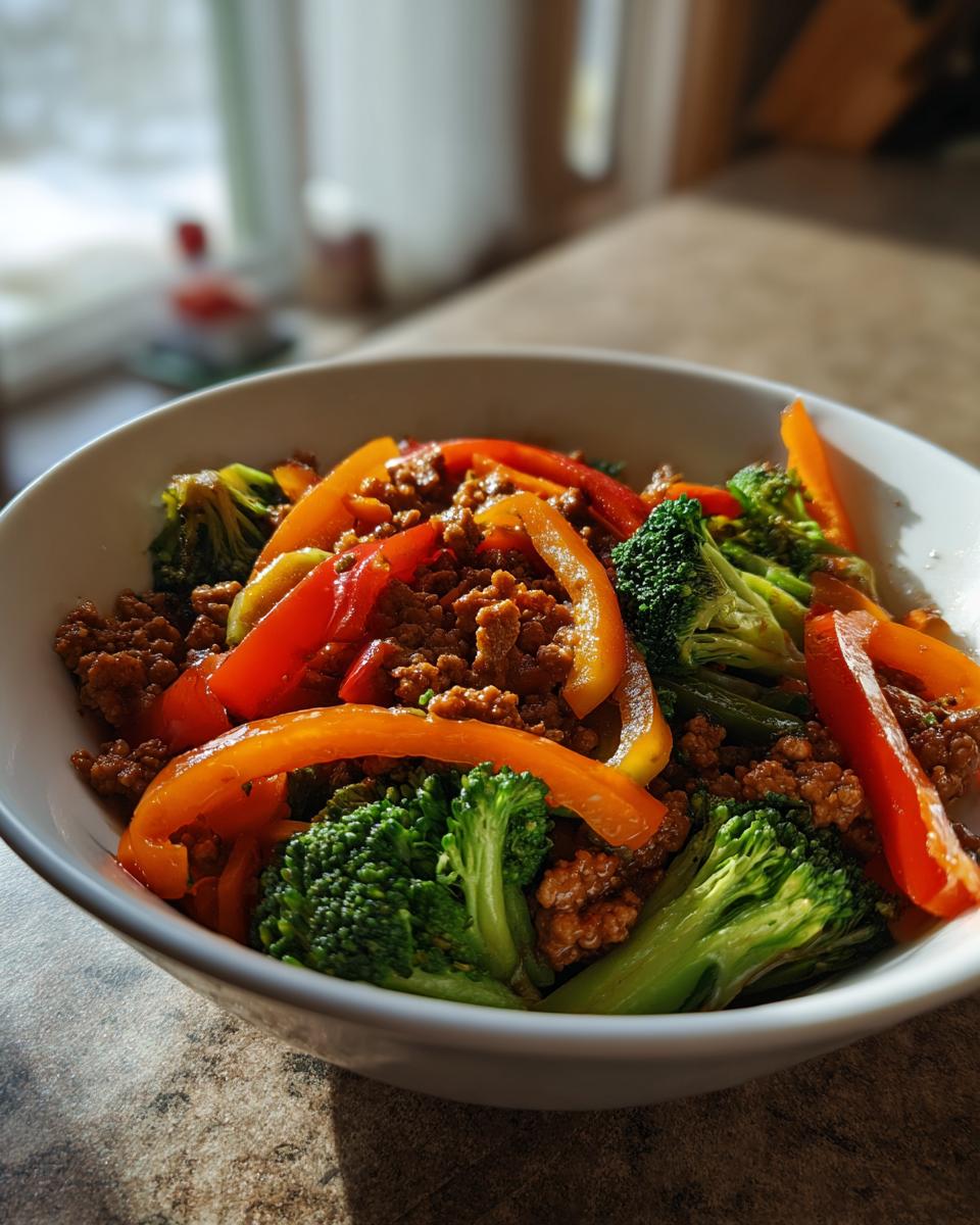 A bowl of delicious ground turkey stir fry with broccoli florets and sliced bell peppers.