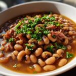 A close-up of a white bowl filled with hearty black-eyed peas and shredded pork, garnished with fresh parsley, perfect for New Year's Day food.