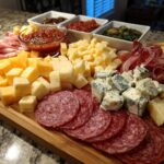 A beautifully arranged charcuterie board featuring various cheeses, cured meats, and dips, perfect for New Year's Eve snacks.