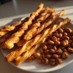 A plate of golden-brown twisted pastry sticks and glazed nuts, perfect for New Years snacks.