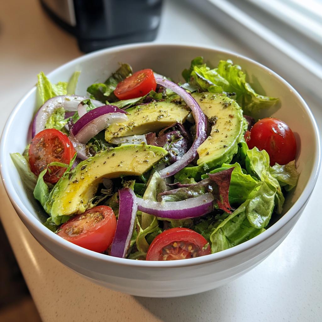 A vibrant bowl of healthy lunch ideas featuring a fresh avocado salad with cherry tomatoes and red onion.