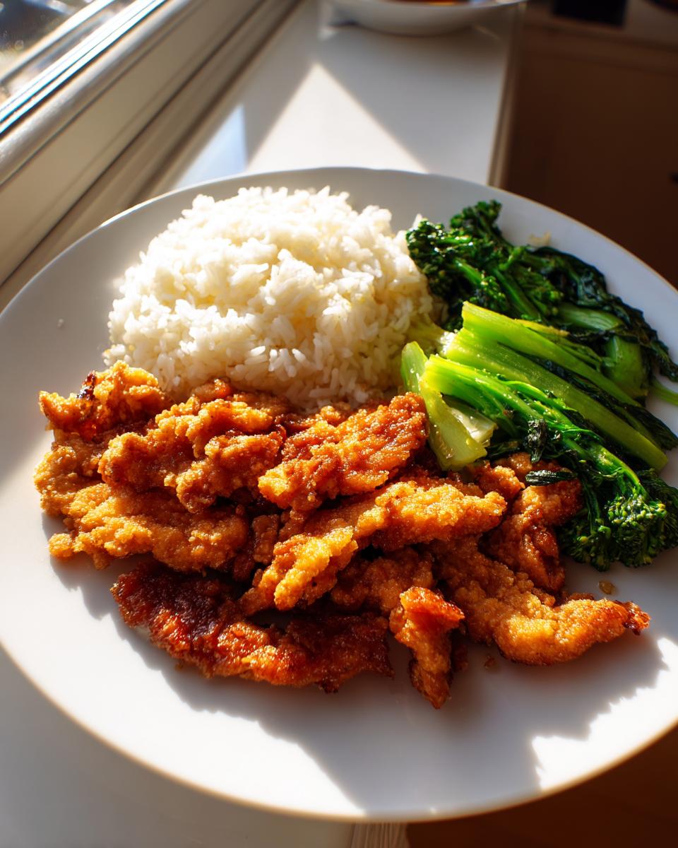 A plate of crispy fried chicken strips, fluffy white rice, and steamed greens, perfect for quick dinner recipes.
