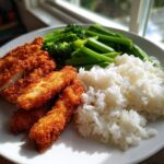 A plate of crispy fried chicken strips served with white rice and steamed broccoli and green beans, perfect for quick dinner recipes.