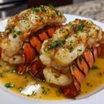 Two succulent lobster tails cooked in garlic butter and garnished with parsley, part of a lobster tail recipe.