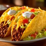 Three savory ground beef tacos filled with seasoned meat, shredded lettuce, cheese, tomatoes, and sour cream.