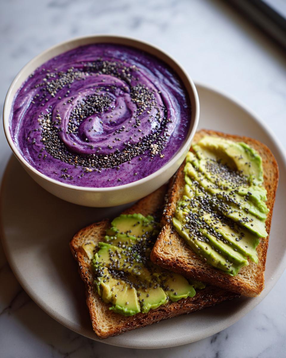 A vibrant purple smoothie bowl topped with chia seeds, served alongside avocado toast. Healthy breakfast ideas.