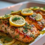 Close-up of baked salmon fillets with lemon slices and dill, part of delicious salmon recipes.