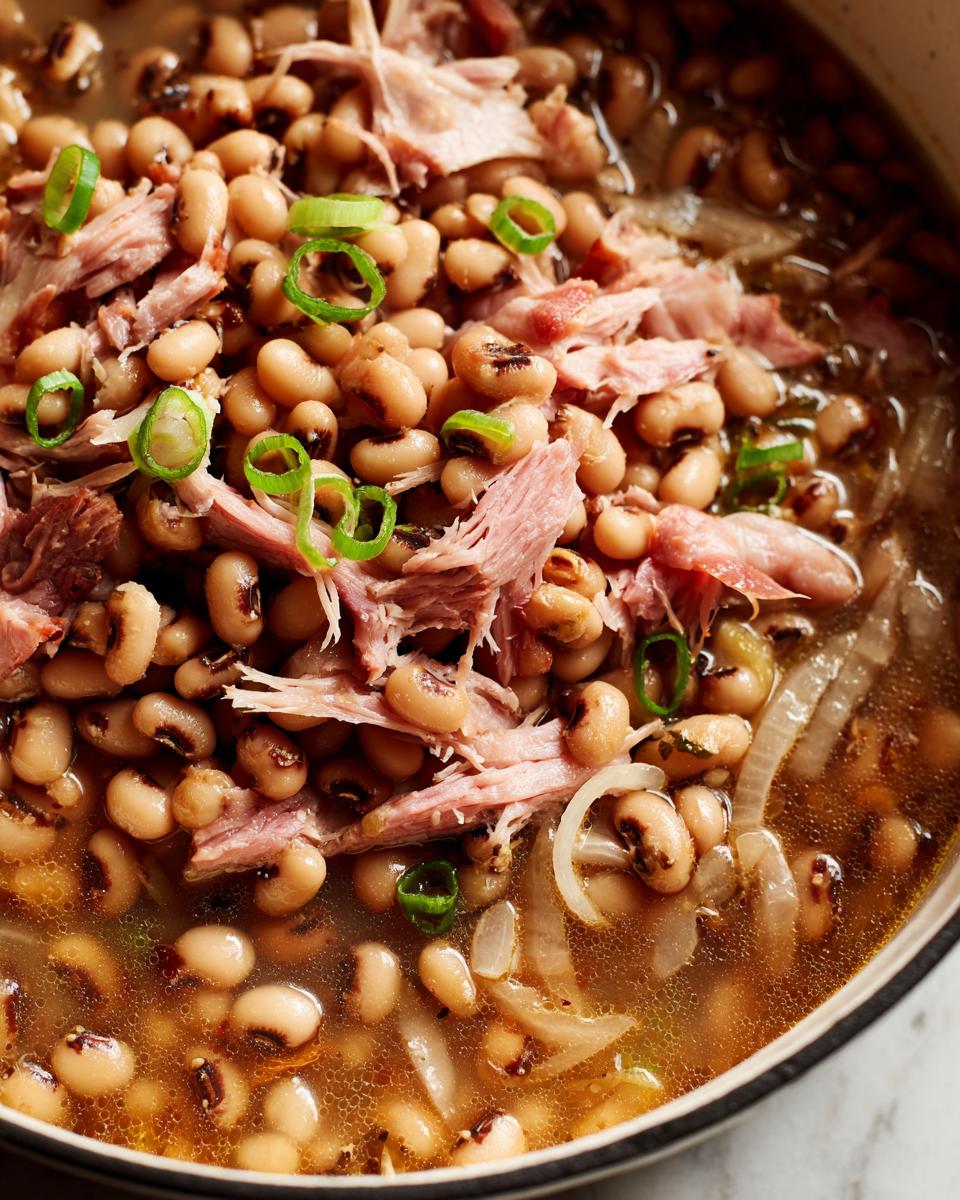 Close-up of a pot of black-eyed peas with shredded pork and green onions, a traditional New Year's Day food.
