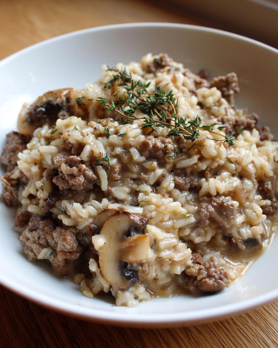 Close-up of one pot beef and mushroom rice pilaf garnished with fresh thyme in a white bowl.