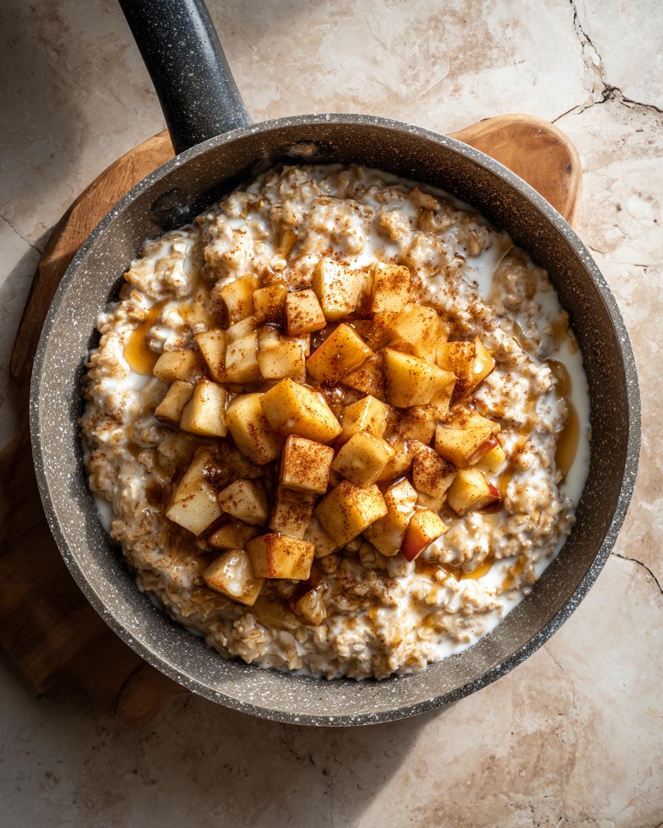 Cinnamon apple skillet oatmeal breakfast topped with diced cinnamon apples and syrup in a pan