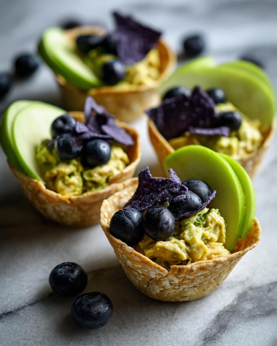 Earth day themed snacks in oat cups with blueberries, green apple slices, and purple chips.