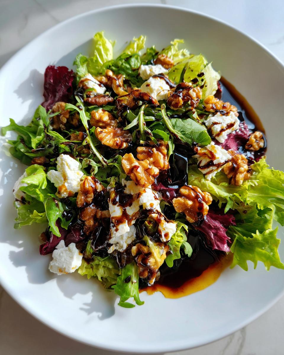 Plate of salad with goat cheese, walnuts, mixed greens, and balsamic glaze drizzle