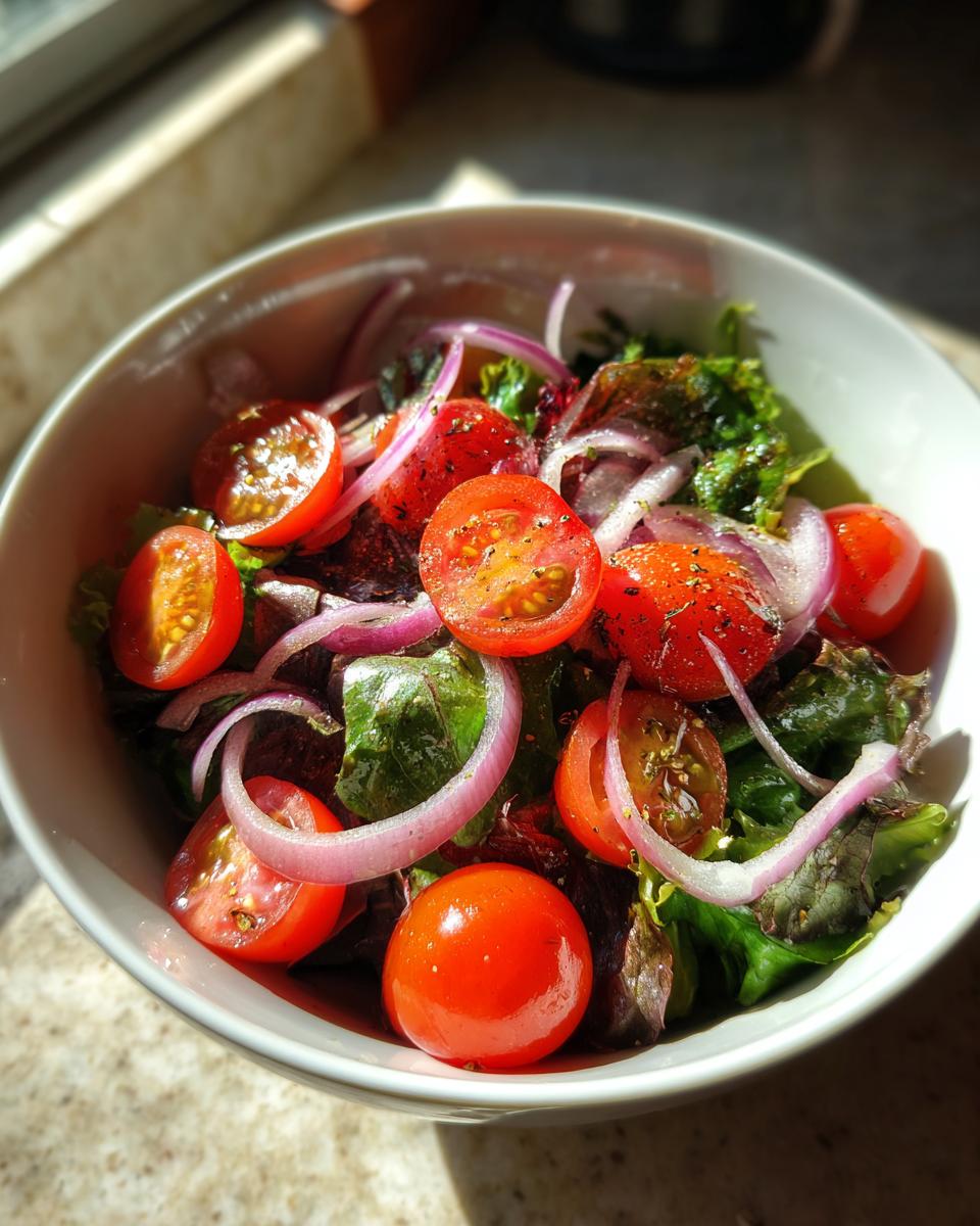 Bowl of fresh cherry tomato salad with red onions and leafy greens for spring light dinner ideas
