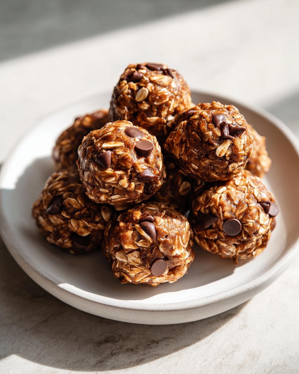 Close-up of chocolate chip no bake snack balls stacked on a white plate.