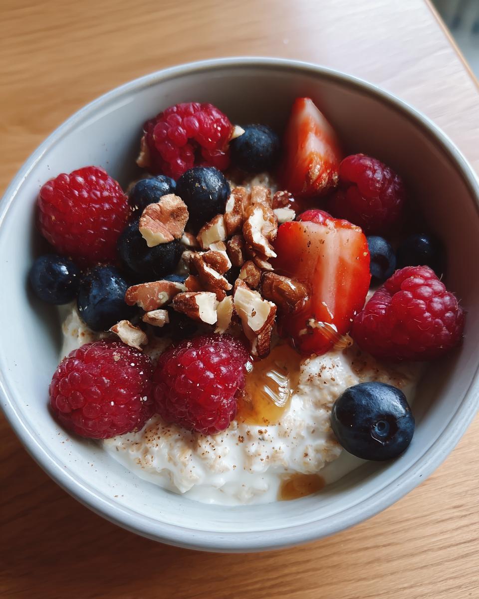 Bowl of easy breakfast meal prep with oatmeal, raspberries, blueberries, strawberries, and chopped nuts.
