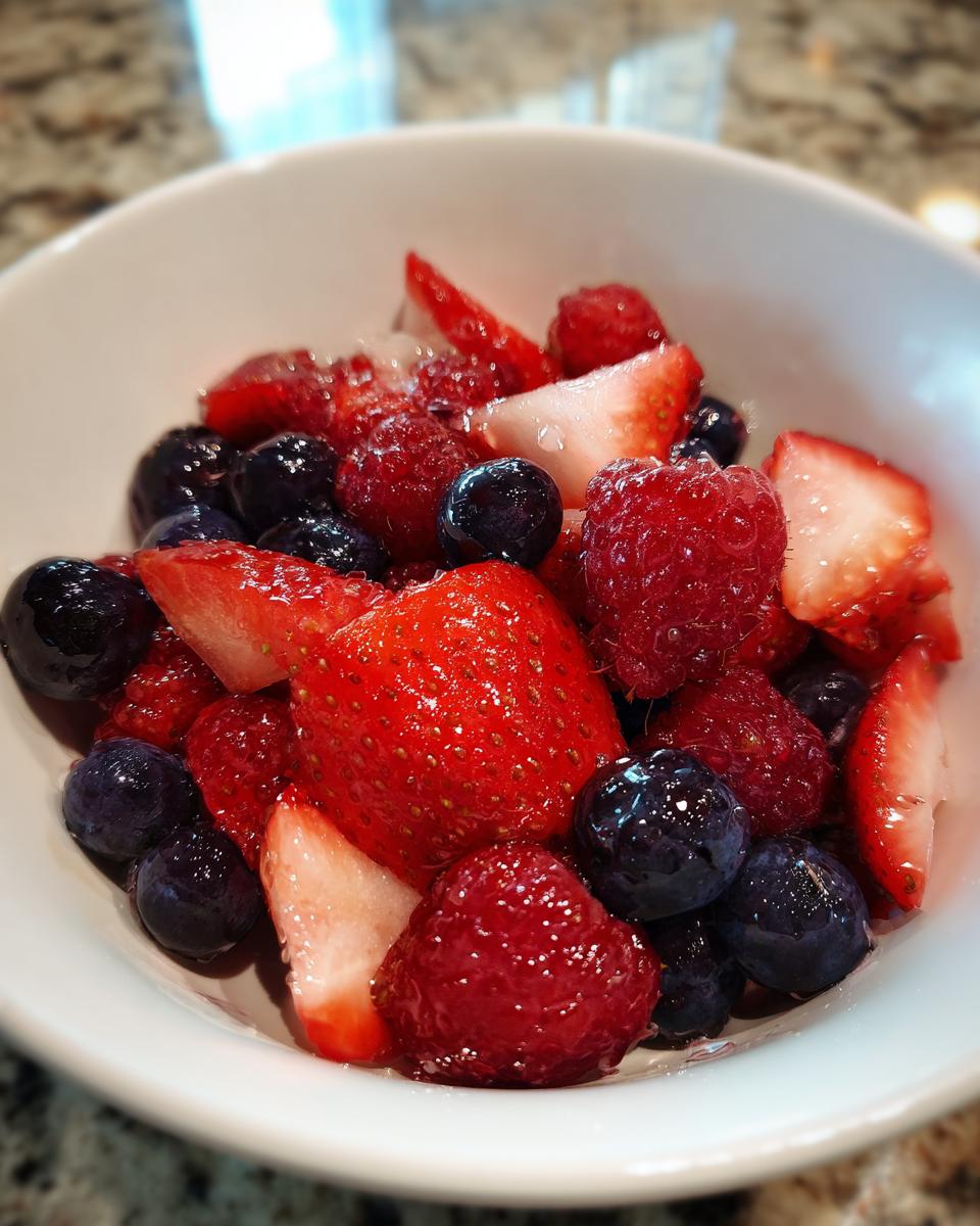 Close-up of fresh strawberries, raspberries, and blueberries in a white bowl, a spring berry sweet treats dish