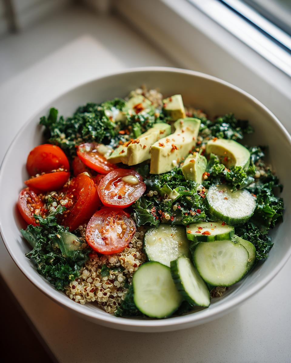 Healthy grain bowl recipes with quinoa, avocado, cherry tomatoes, kale, and cucumber slices.