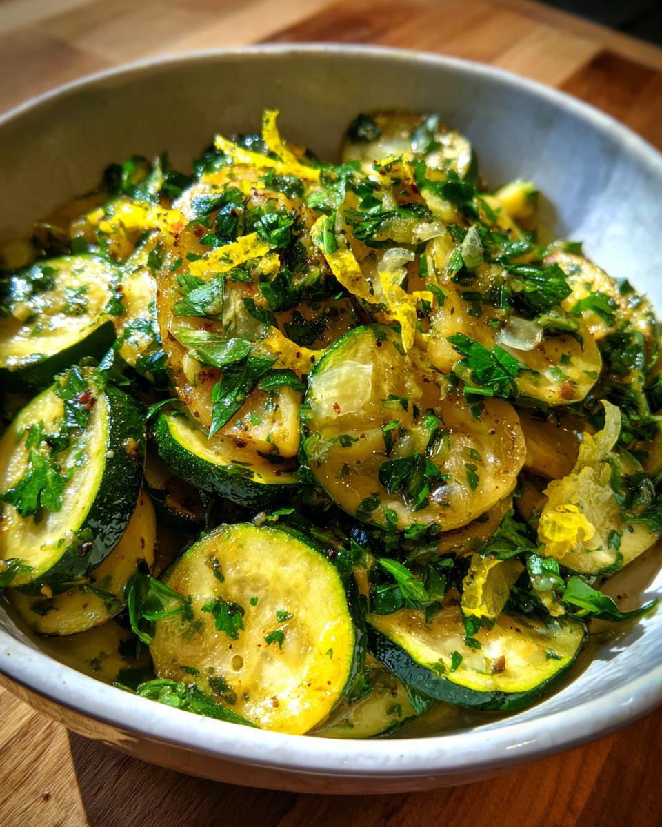 Bowl of sautéed zucchini slices mixed with fresh herbs and lemon zest, a spring zucchini recipes dish.