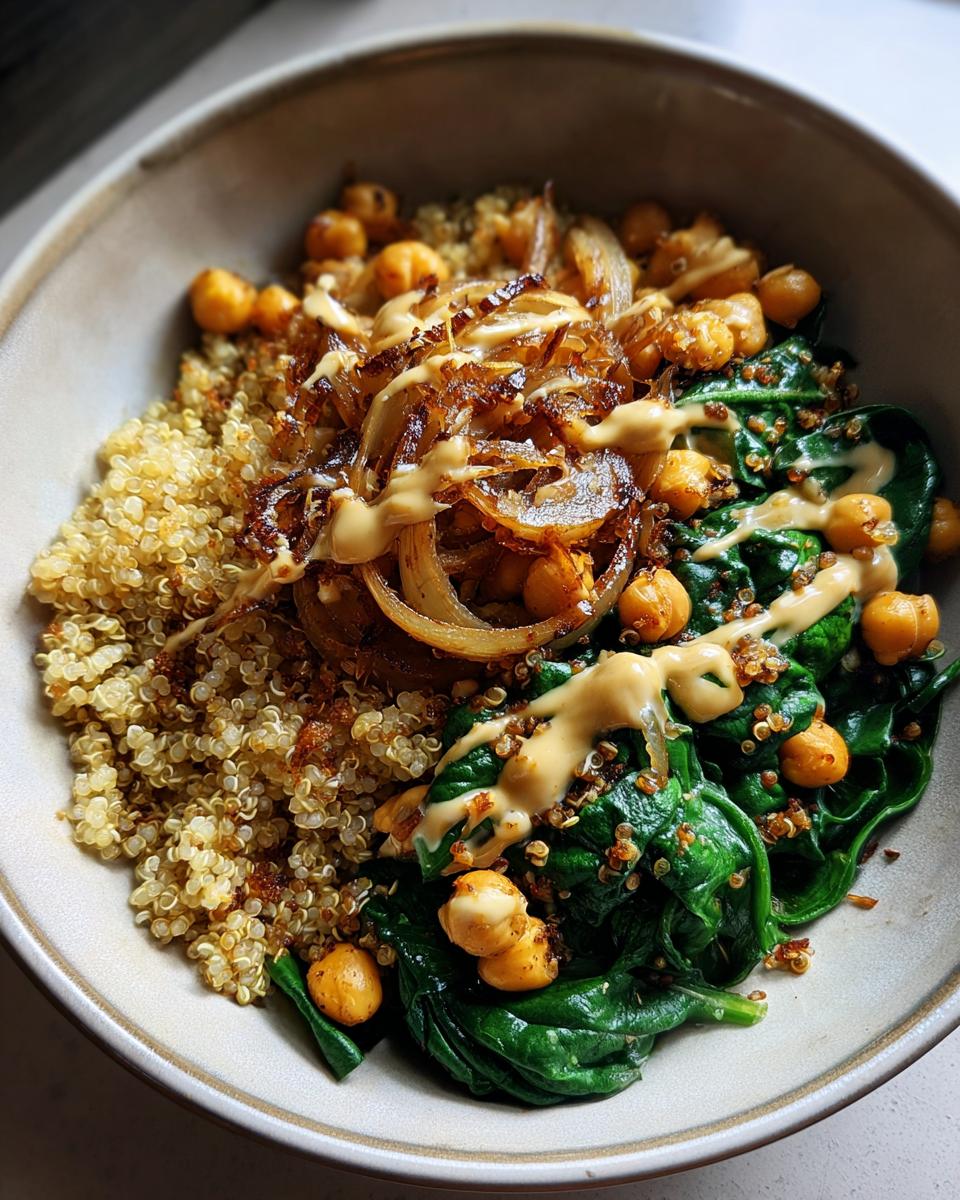 Bowl of quinoa, sautéed spinach, chickpeas, caramelized onions, and sauce for simple vegan dinner recipes