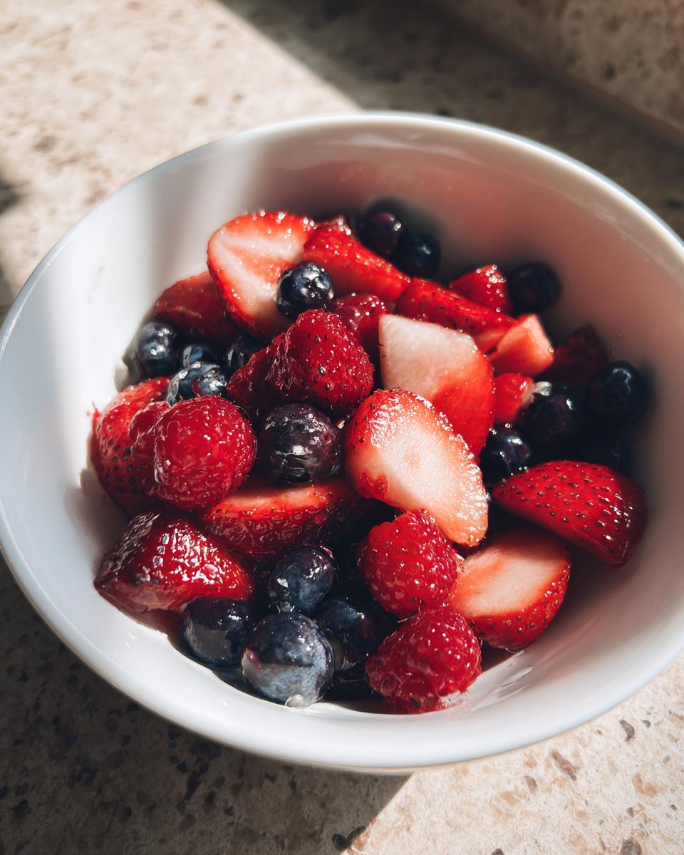 Bowl of fresh spring berry sweet treats with strawberries, blueberries, and raspberries.