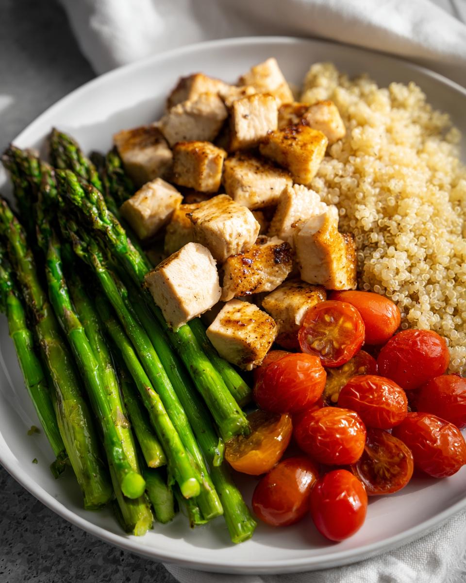 Plate of spring protein packed meals with grilled chicken, asparagus, quinoa, and roasted cherry tomatoes.